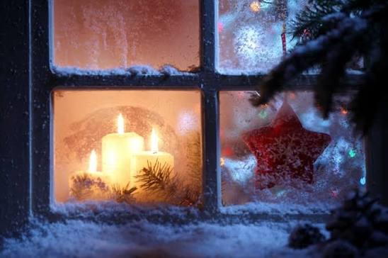 Candles glowing behind a frosted window at Christmas