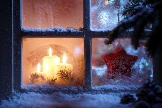 Candles glowing behind a frosted window at Christmas