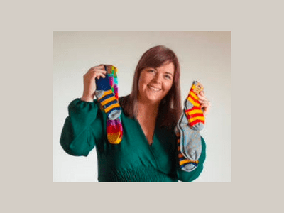 Polly from Polly and Andy holding her signature colourful bamboo socks, available in The Book Resort gift boxes.